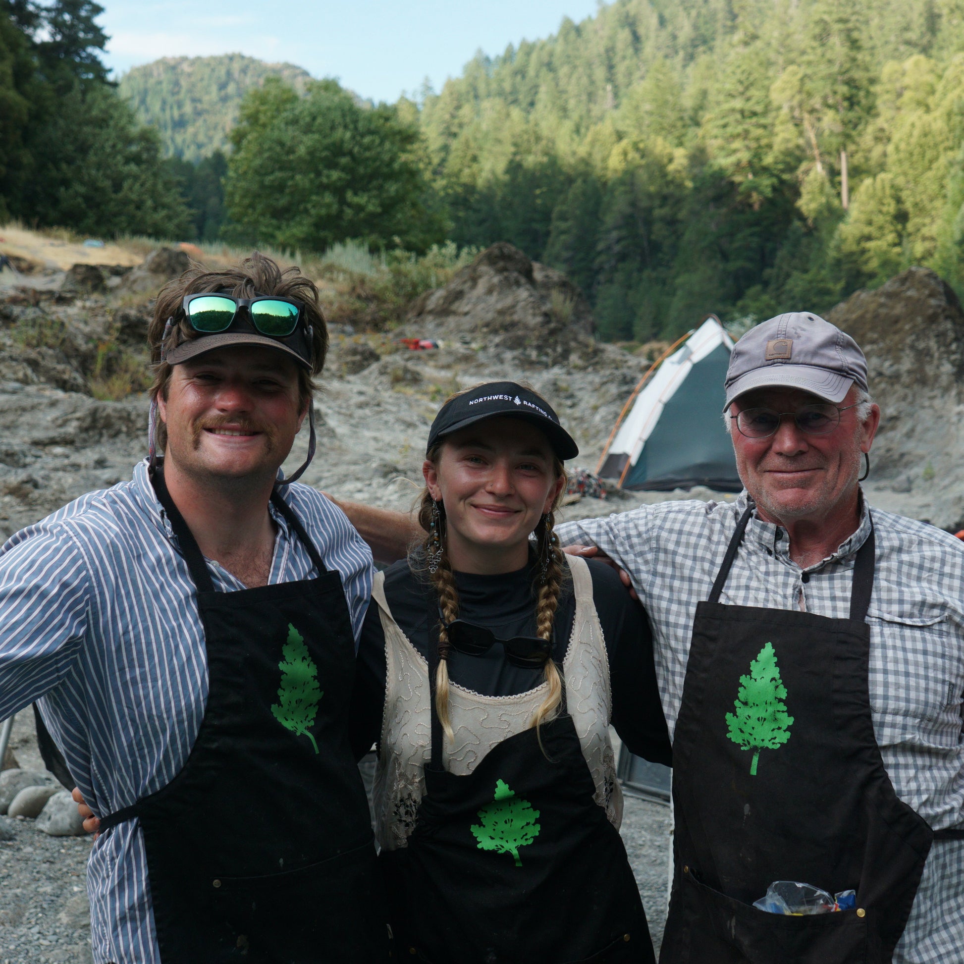 Three people wearing aprons with a forest background